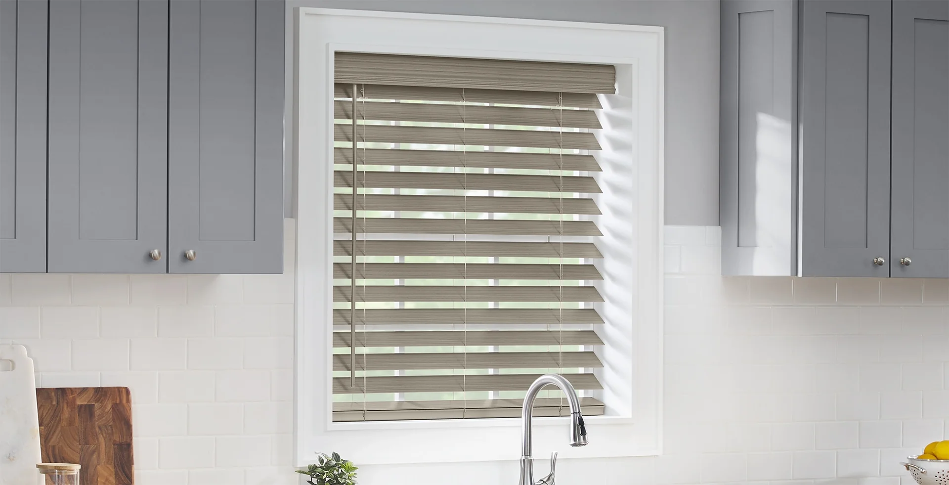 Grey faux wood blinds on a kitchen window