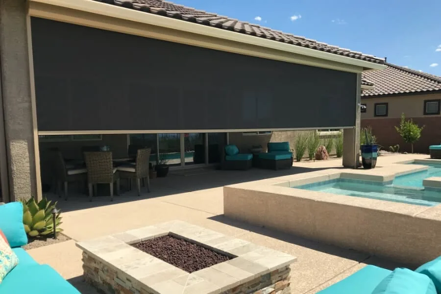 Fire Pit and Pool, a charcoal solar shade fully lowered across a covered patio beside a fire pit and pool