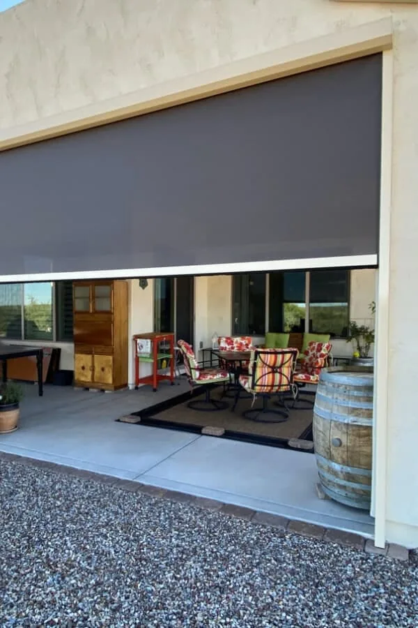 A motorized solar shade stopped partway down over a Phoenix patio dining area, shading the low sun while the view below stays open
