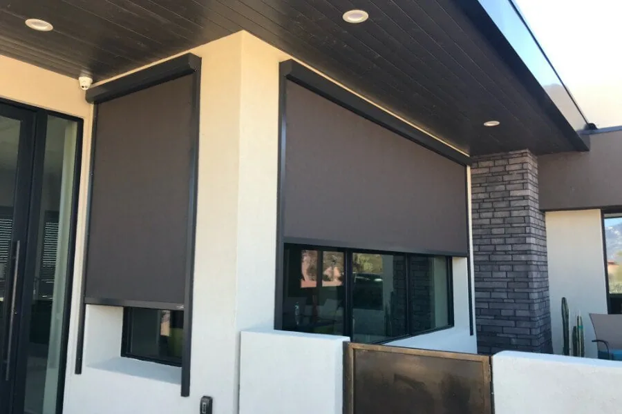 Modern Architectural, bronze solar shades in dark frames lowered on a contemporary Phoenix home with a stacked stone column