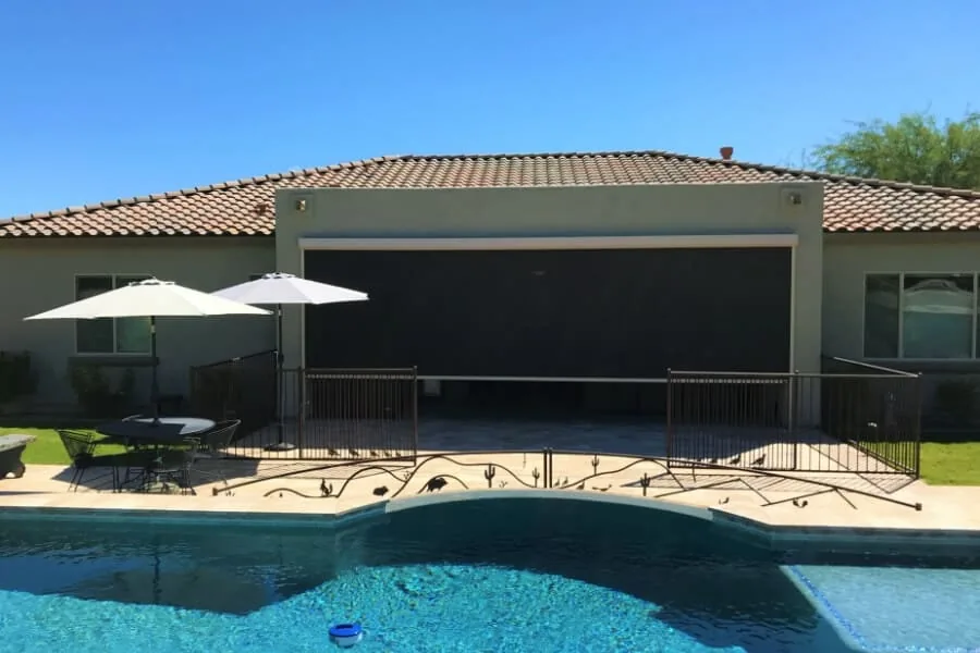 One Wide Panel, a single wide solar shade lowered across the full patio opening of a tile-roof home seen from across the pool