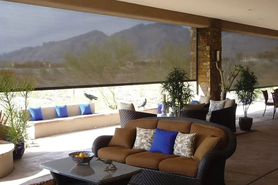 Outdoor Living Room, a long run of solar shades lowered around a furnished patio with the mountains visible through the mesh