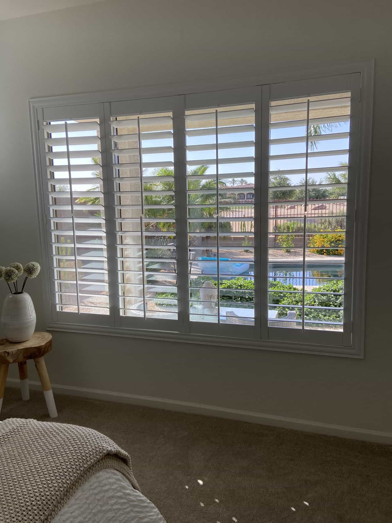 Polywood shutters in a bedroom with a pool view