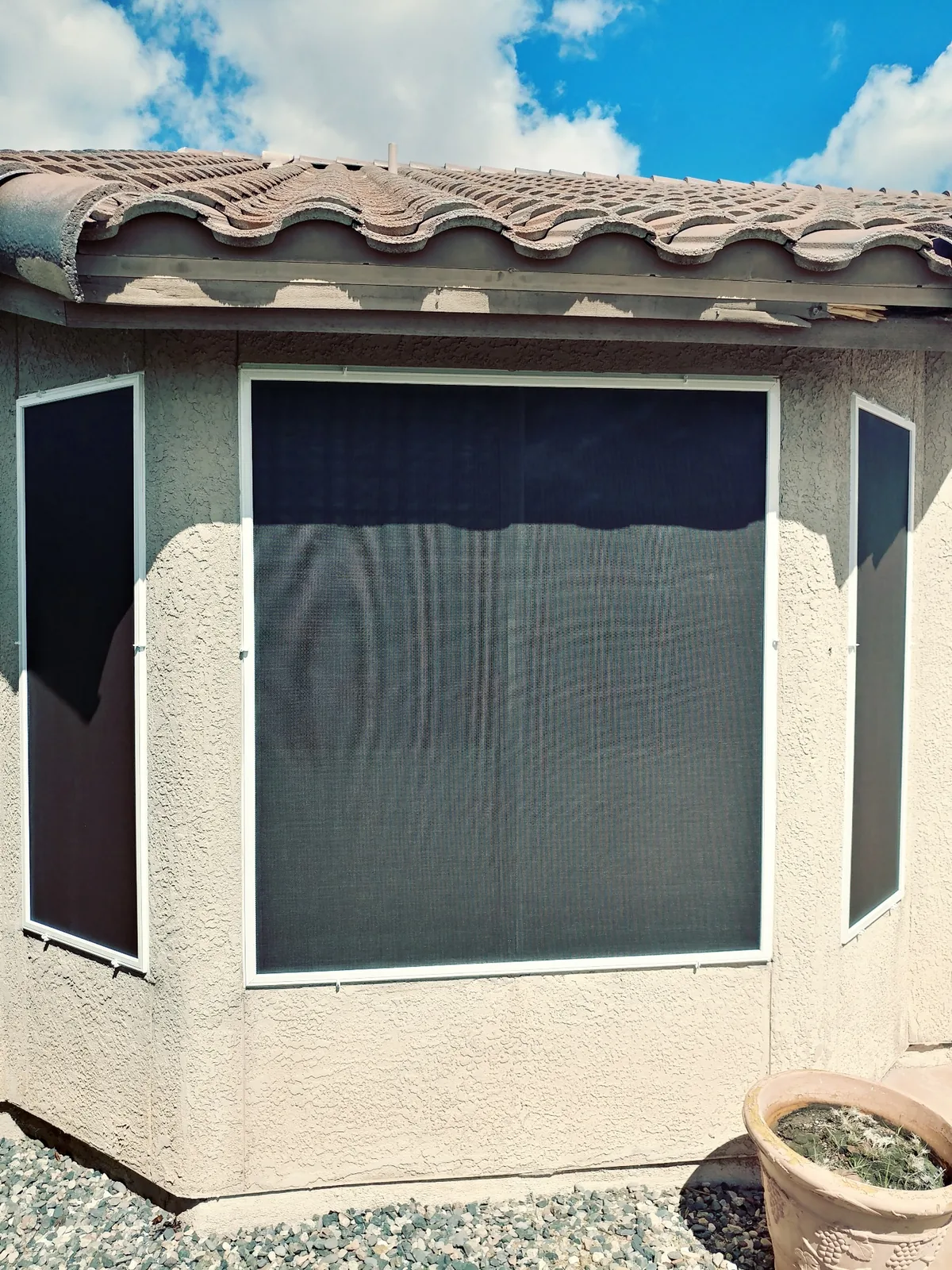Bay Window Group, three sun screens wrapping a bay window where raking sunlight makes the weave and the view through it visible