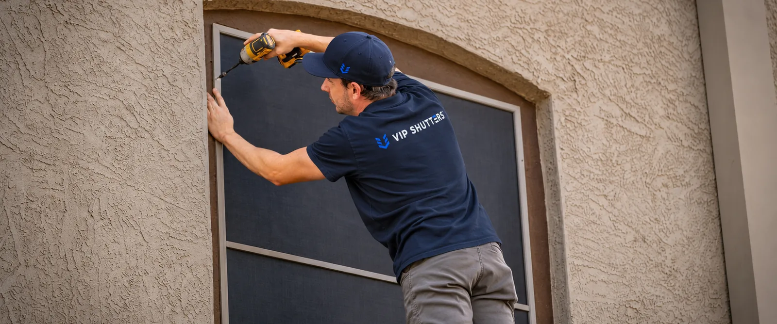 Installed To Fit, a VIP Shutters installer fastening a screen frame built to follow the curve of an arched window opening
