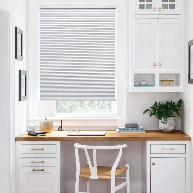 White cordless blackout cellular shade above a desk nook
